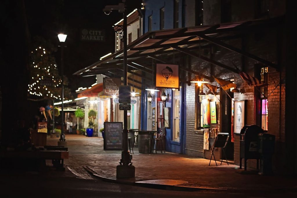 A dark corner in City Market Savannah at night with shops dimly lit by street lamps
