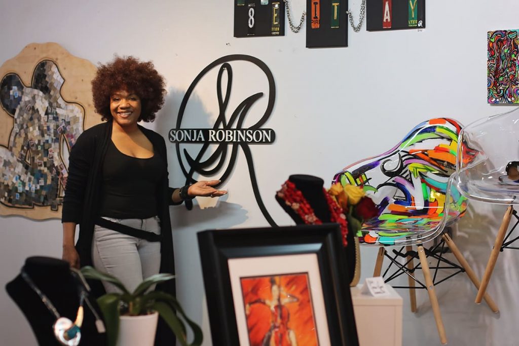 Artist Sonja Robinson stands next to the art in her gallery in Savannah's City Market
