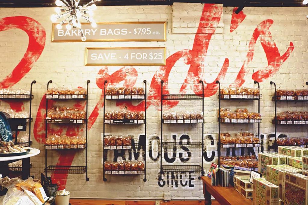 Shelves holding bags of cookies displayed on a white brick wall with the word Byrd's hand-painted on it in red