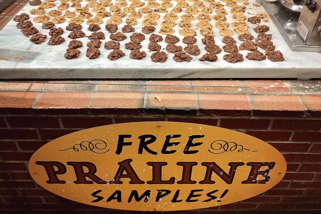 A marble slab covered in pralines with a yellow sign that reads Free Praline Samples!