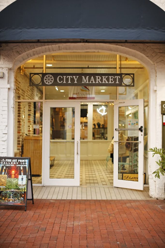An open glass door with a sign above it reading City Market