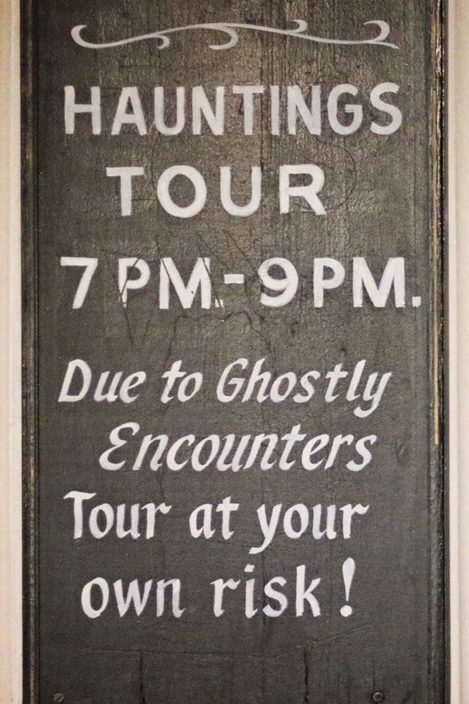 Hand-painted ghost tours in Savannah sign with white text on a black background that reads "Due to Ghostly Encounters - Tour at your own risk!"