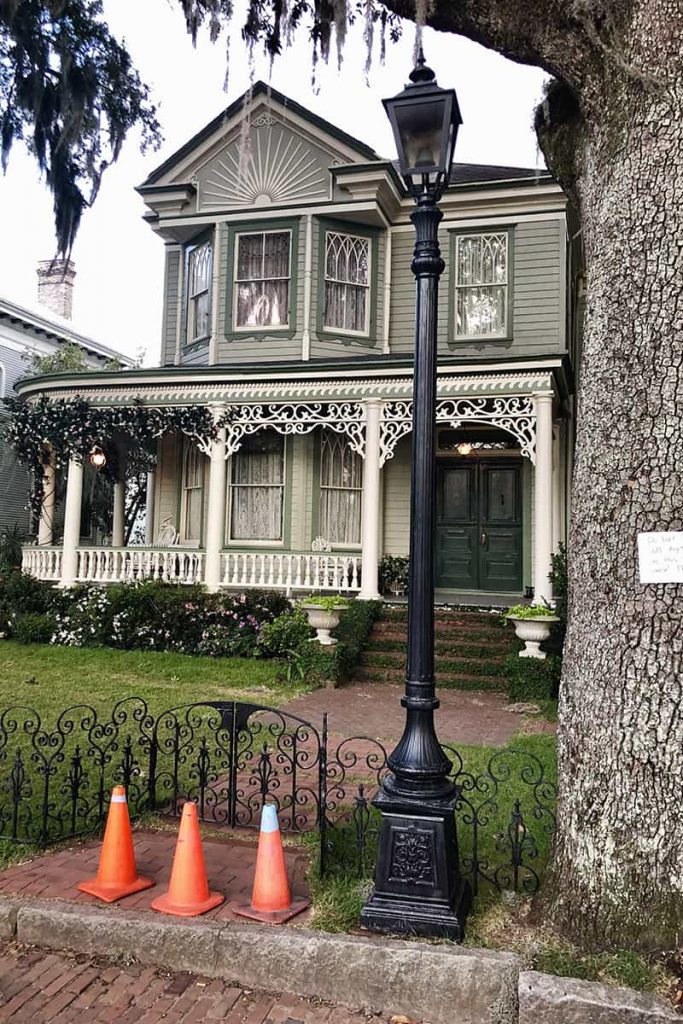 A black wrought-iron gas lantern and three traffic cones are placed on the sidewalk leading up to a Victorian-style home