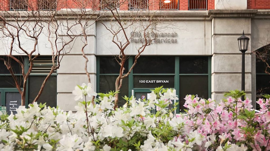 Pink and white azaleas with the Bryan Street Parking Garage sign and entrance in the background