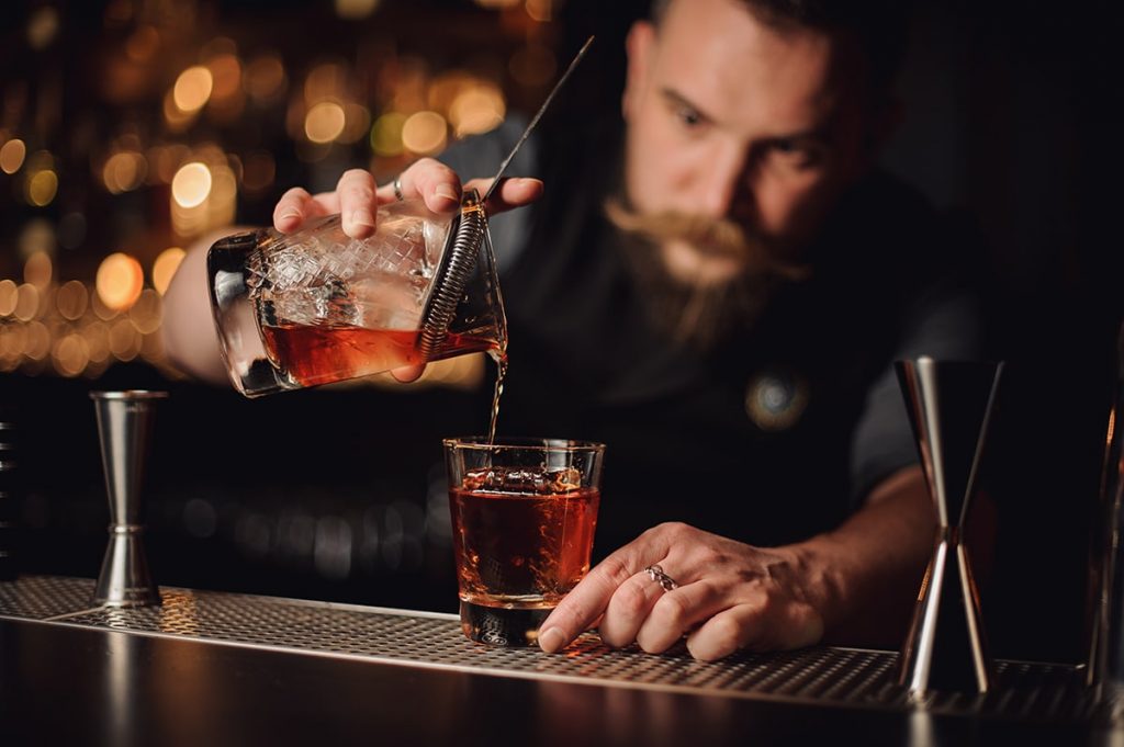 A genteel bartender concentrates on pouring a drink