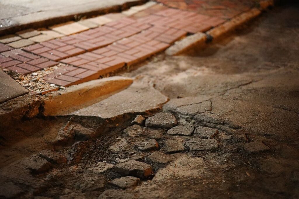 A bumpy road in Savanah with multiple different surfaces visible, from stamped concrete to dirt to asphalt to brick