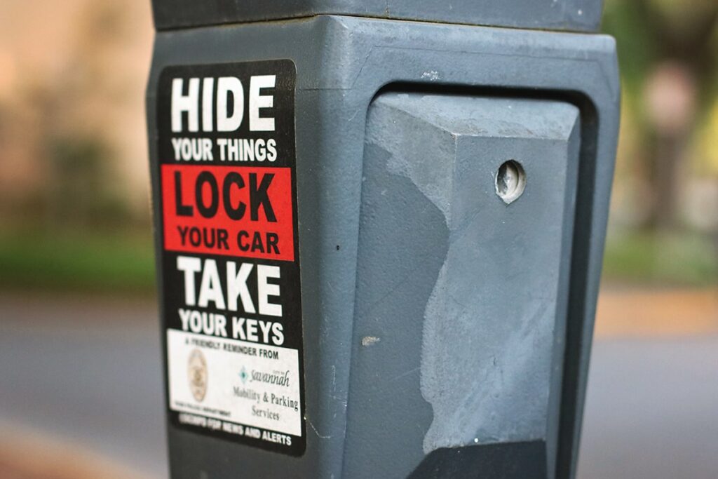Stickers on the side of a parking meter in Savannah include the following safety message "Hide your things, lock your car, take your keys"