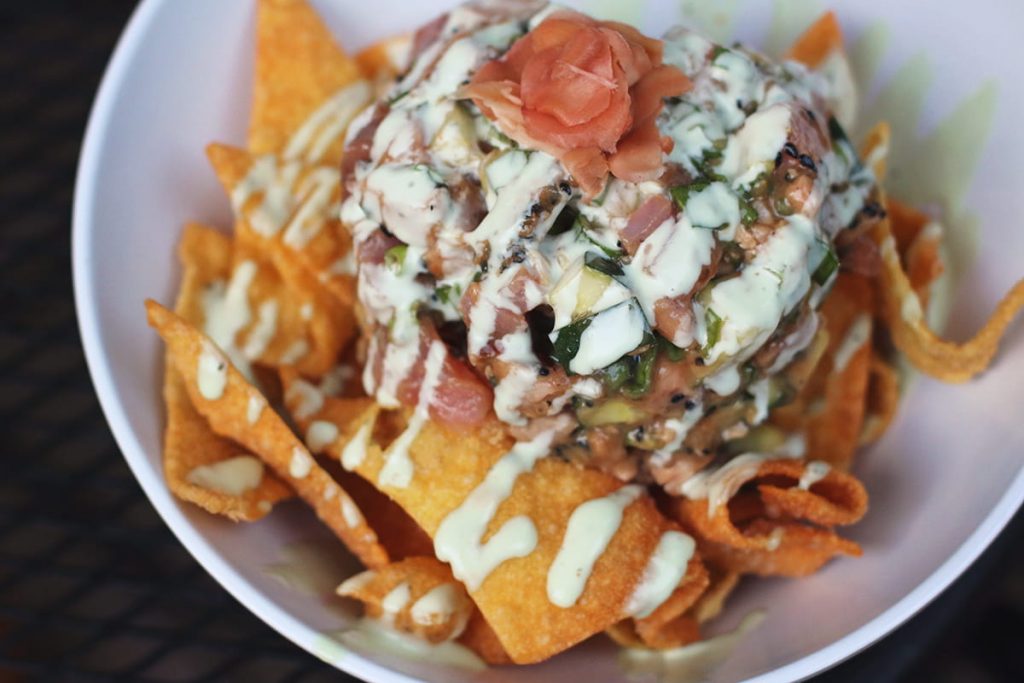 Close up of a bowl of tuna tartare on a bed of crispy wontons artfully drizzled with cucumber wasabi cream at Driftaway Cafe