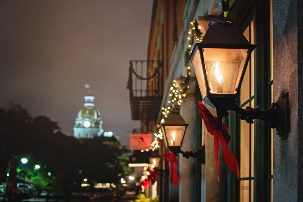 Gas lanterns with red ribbons and greenery draped on Savannah's River Street Inn