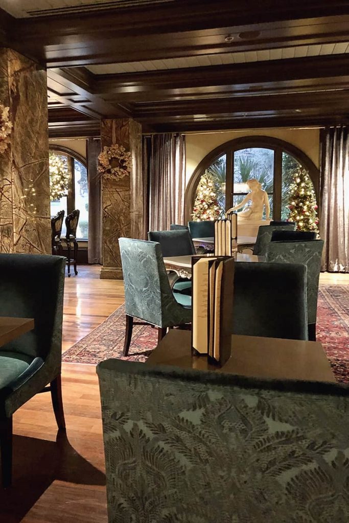 Lobby of the Mansion on Forsyth showing blue velvet chairs, gold-trimmed walls, feathered Christmas trees, and wreaths made of white feathers