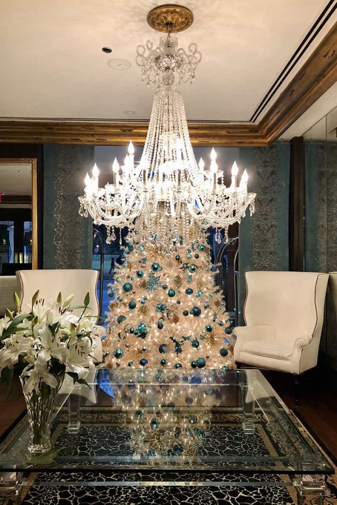 The Mansion on Forsyth Park is one of the hotels in Savannah that decorate for Christmas, as seen by this seating area white feathered Christmas tree decorated with gold and blue crystal orbs