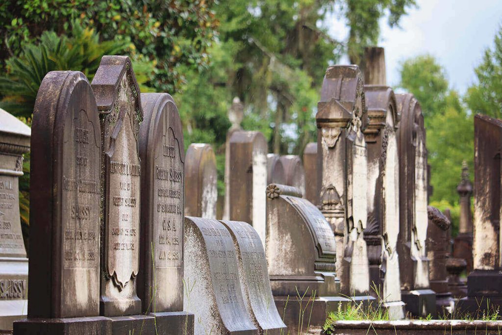 Double rows of old headstones in Laurel Grove Cemetery. The headstones are off-white towards the center and dark brown with age on the edges