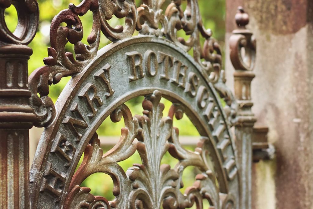 Close up of an elaborate cast iron gate in Laurel Grove Cemetery. The iron is shaped into intricate scrolls above a curved portion with the name Henry Rothschild in raised lettering