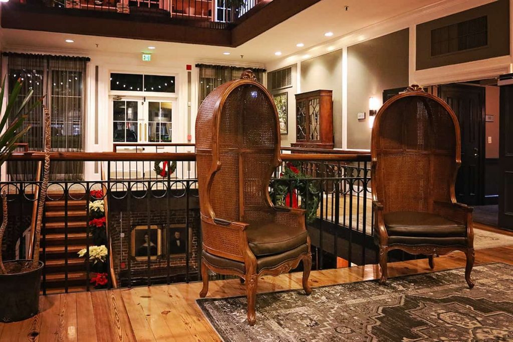 Two leather chairs in the lobby of River Street Inn at Christmastime with wreaths and holiday decor in the background