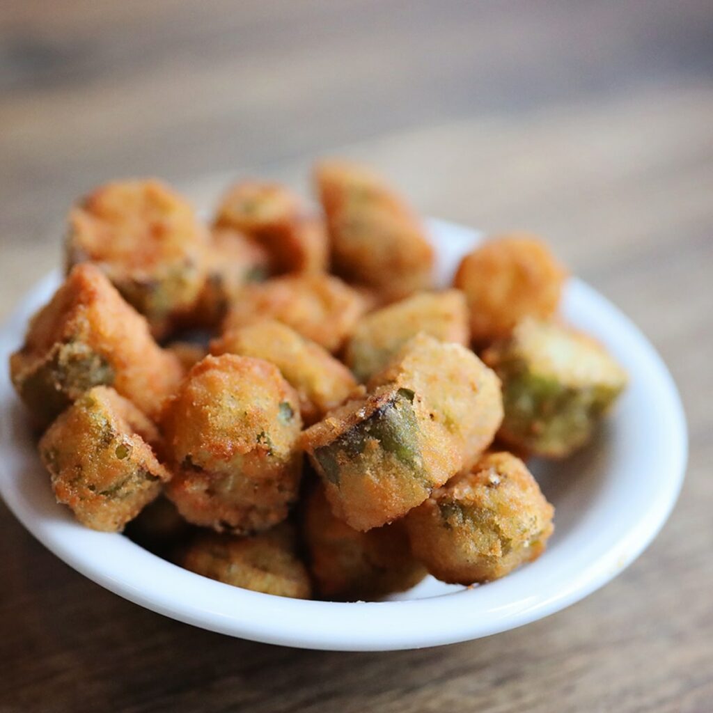 White bowl filled with fried okra. The batter is light and fried to golden perfection