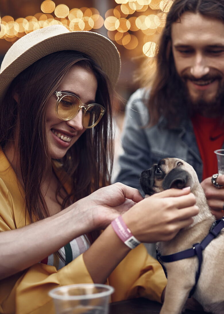 Three young adults with a hipster vibe gather around a cute dog at a restaurant in Savannah, giving him lots of friendly attention