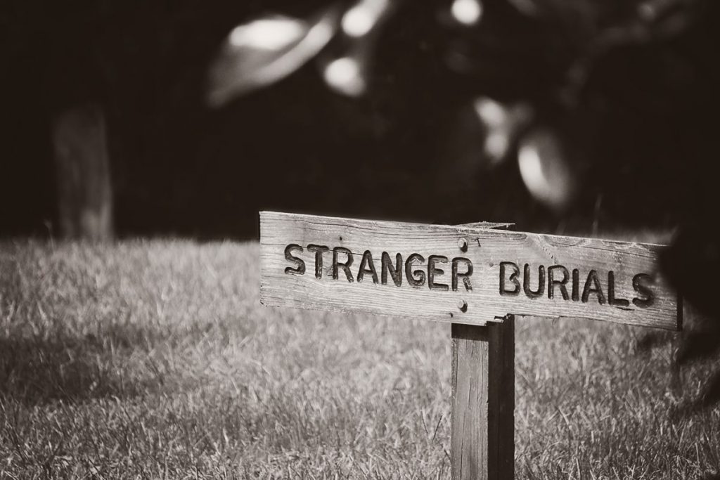 A wooden sign in Laurel Grove Cemetery with the words "Stranger Burials" etched into the surface