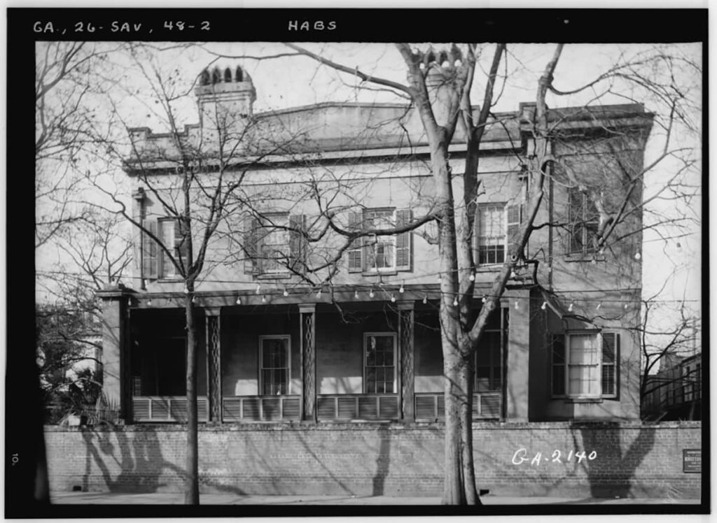 Historic B&W photo of the side of the Sorrel Weed House. The trees near the sidewalk are bare and there are twinkle lights strung across the road