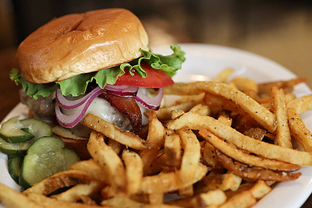 White plate loaded with crispy fries and a burger from Green Truck Pub, which has been voted one of the Best Restaurants in Savannah for ten years in a row