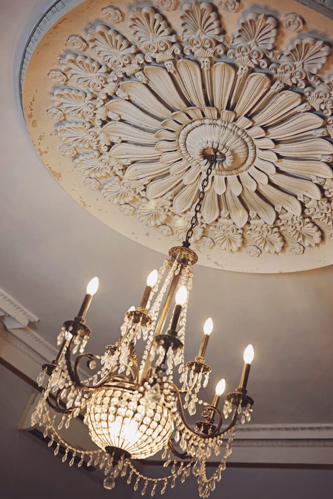 A beautiful brass and crystal chandelier hangs from a massive (probably 8-foot diameter) and intricate plaster off-white ceiling medallion at the Sorrel-Weed House
