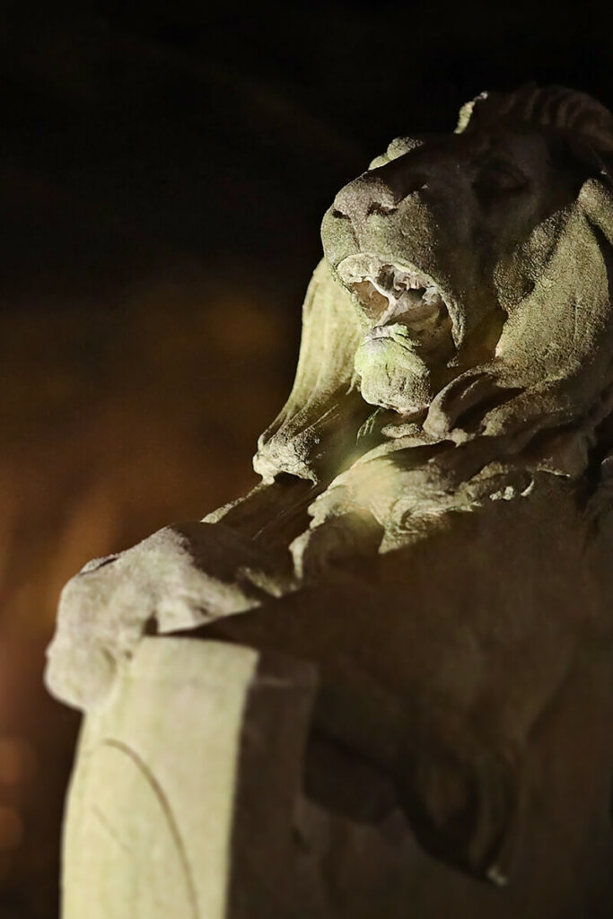 Nighttime scene of a growling lion statue, lit eerily from below