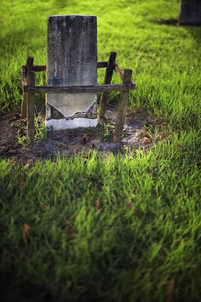 A spooky backlit headstone in Colonial Park Cemetery, surrounded by wooden stakes