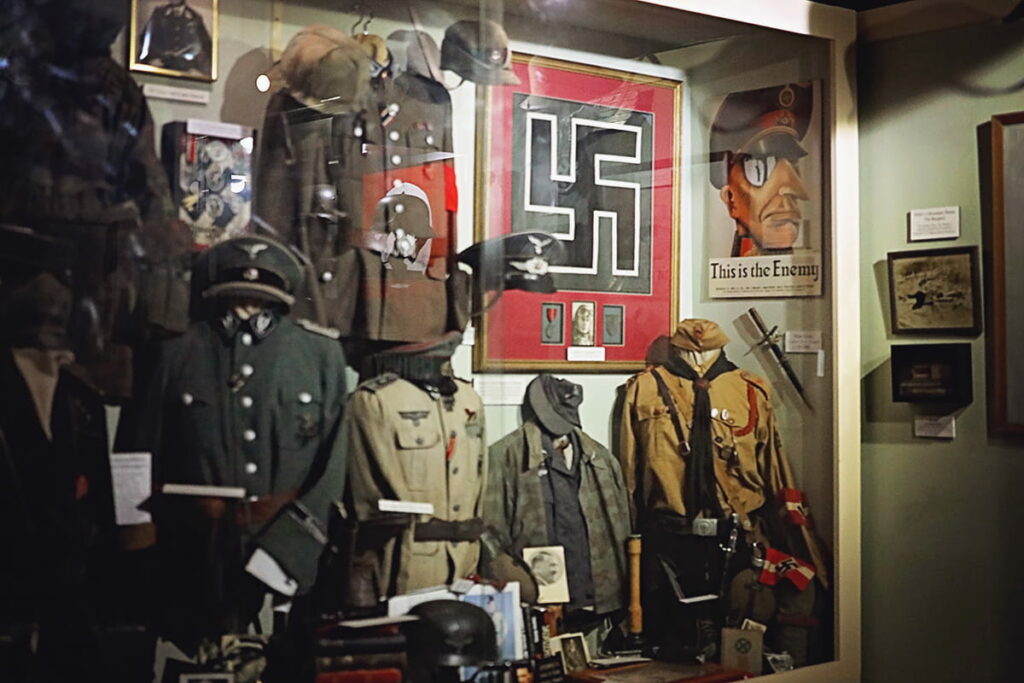 Display case filled with WWII uniforms and propaganda inside Webb Military Museum in Savannah