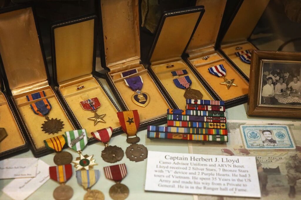 Collection of military medals on display inside Webb Military Museum for Captain Herbert J. Floyd. The display includes a Purple Heart and approximately 15 additional types of medals