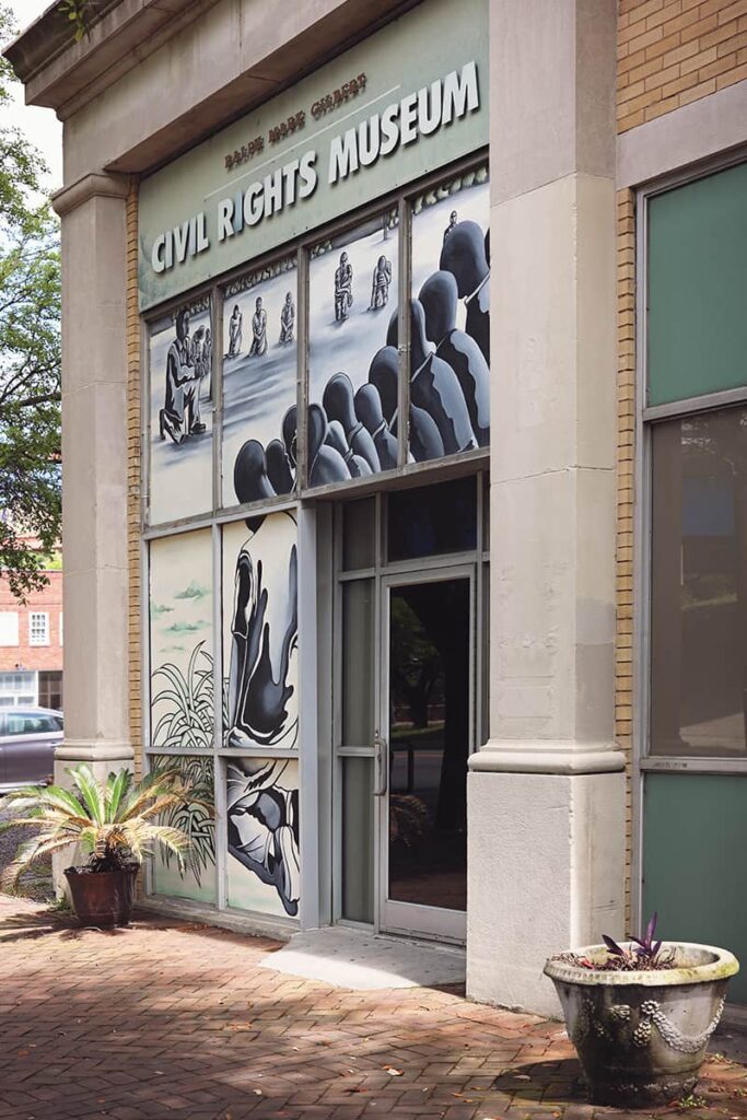 Entrance to the Ralph Mark Gilbert Civil Rights Museum in Savannah with artwork of a group of Black males kneeling covering the exterior windows