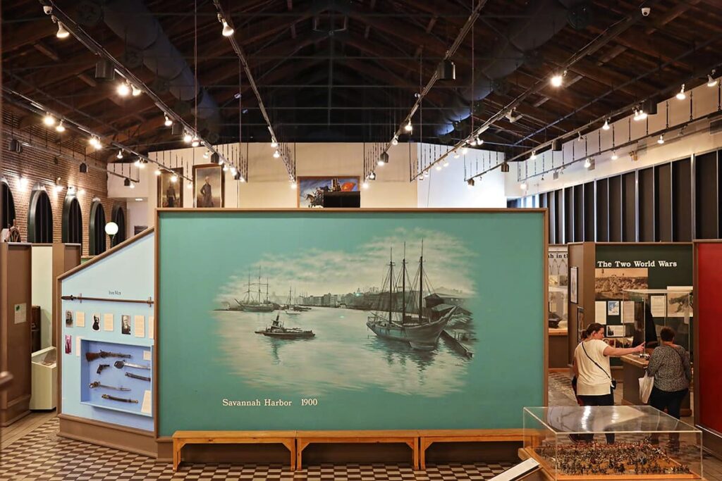 Interior of the Savannah History Museum from a high level looking down at an expanse of displays, including a large painting of of the Savannah Harbor from the year 1900
