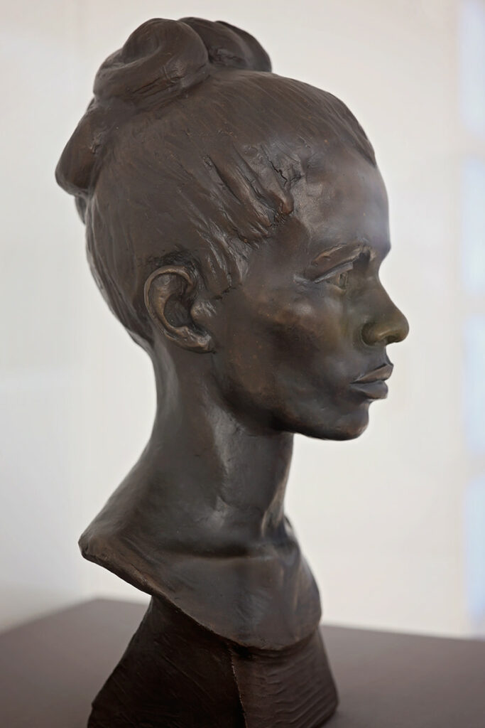 Carved bronze bust of a female with elegant high cheekbones and hair pulled back into a bun