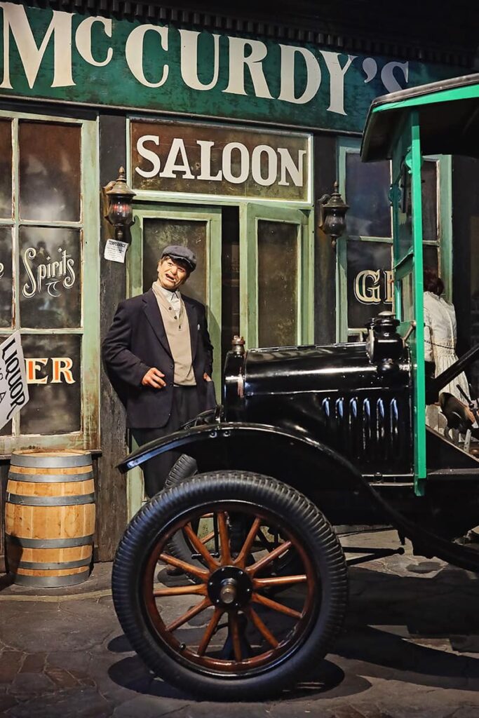 Scene inside American Prohibition Museum showing an old-timey Ford and the wax figure of a man in a suit standing in front of a sign for McCurdy's Saloon
