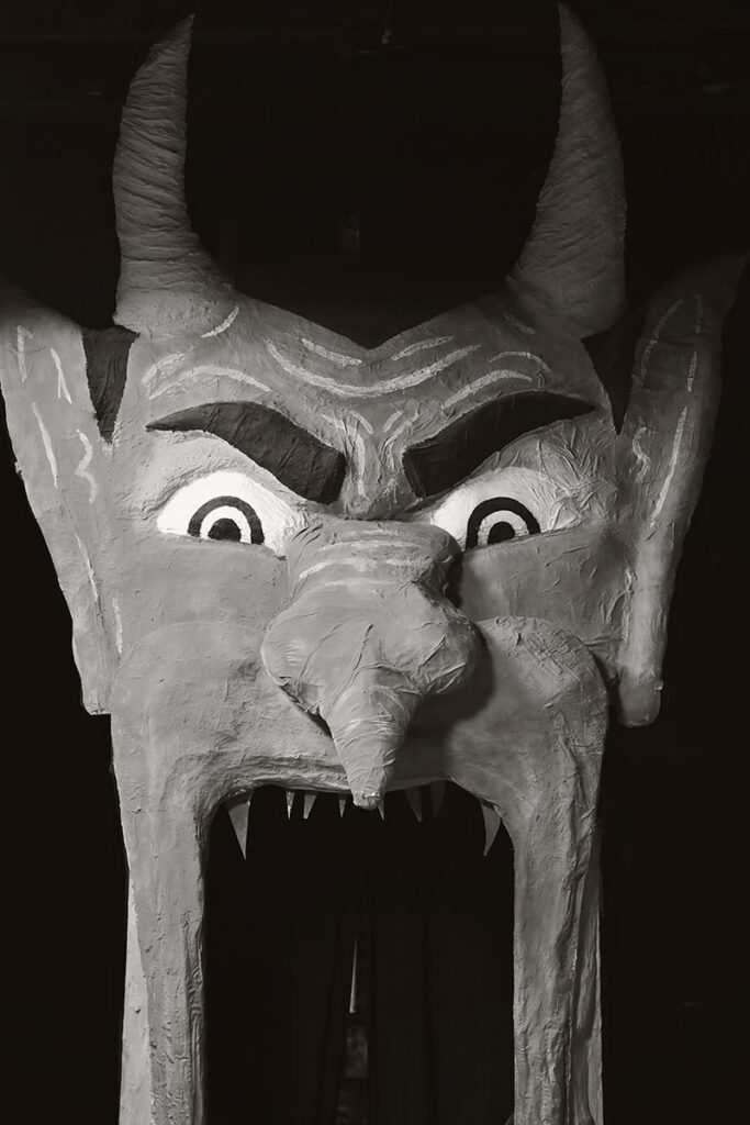 Oversized paper mache devil face with an open mouth that patrons can walk through at Graveface Museum in Savannah