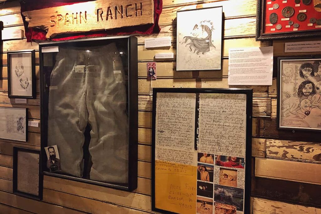 The Manson display at Graveface Museum includes a wall full of Manson photos, drawings, memorabilia, and even clothing items that Manson wore at Spahn Ranch. The Spahn Ranch wooden sign is displayed, as well