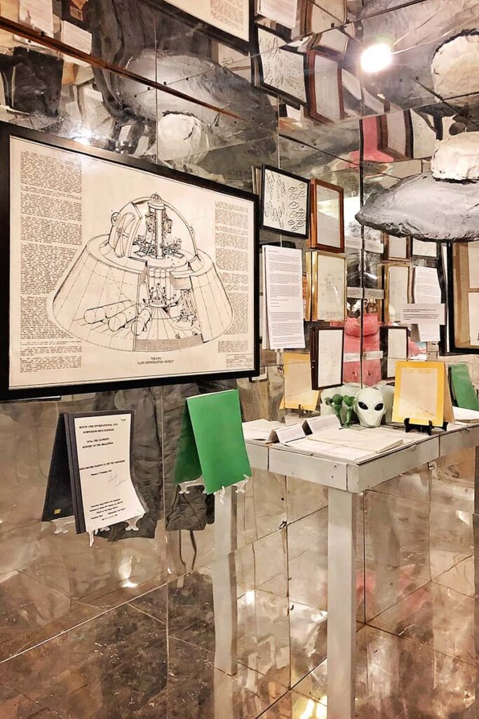The mirrored UFO room at Graveface Museum in Savannah with UFO drawings, newspaper clippings, alien masks, and a paper mache UFO