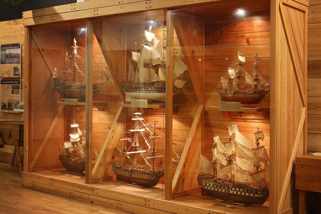A beautiful wooden display case with 6 intricate ship reproductions on display at Massie Heritage Center