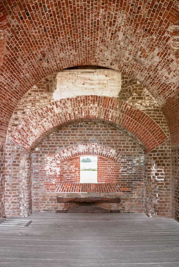 An arched brick window covered with fading white paint at Fort Pulaski on Tybee Island, Georgia