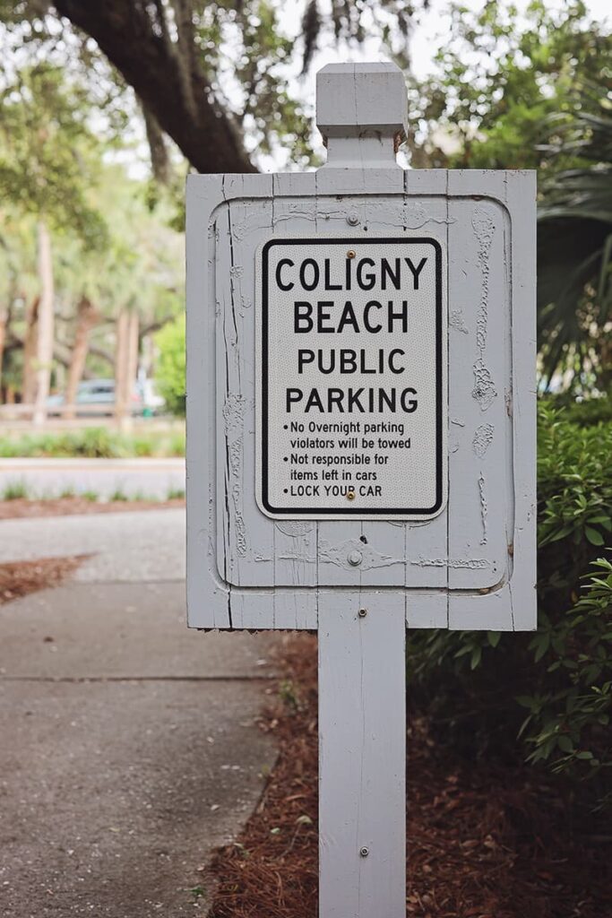 Grey wooden sign indicating the public parking area for Coligny Beach