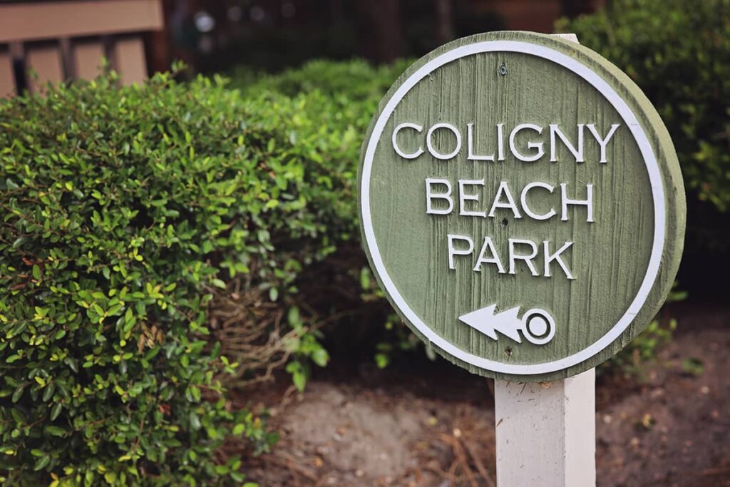 Circular green wooden sign with white lettering that reads Coligny Beach Park