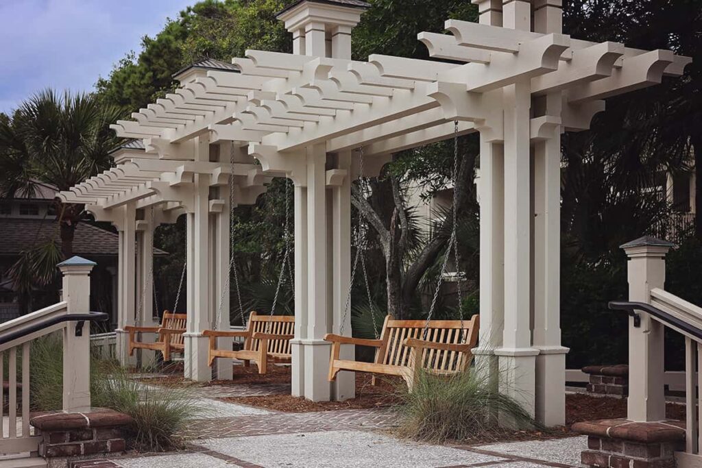 Painted wooden verandas with three wooden swings hanging from them, surrounded by nice landscaping at Coligny Beach Park