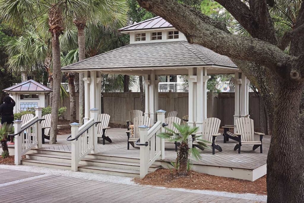 Clean, covered seating area with 10 wooden Adirondack chairs arranged on a nice wooden deck