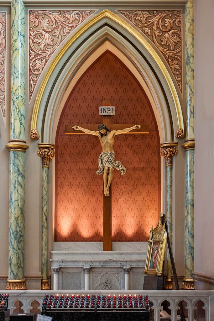 An interior wall inside the Cathedral of St. John the Baptist with a crucifix scene in front of an arched entryway