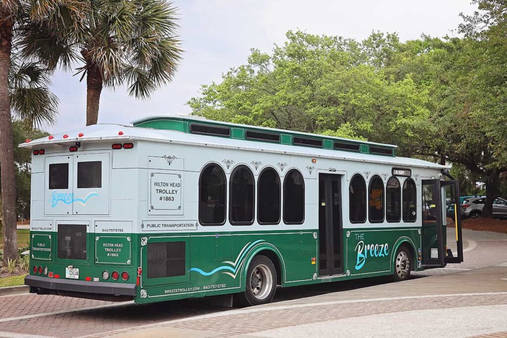 Green and white shuttle nicknamed The Breeze sits parked at a roundabout in Coligny Beach Park