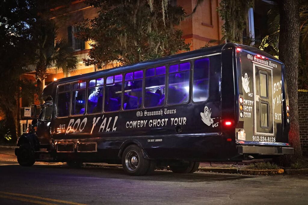 Black trolley with purple tinted windows and the words "Boo Y'all Comedy Ghost Trolley Tour" painted in white on the side