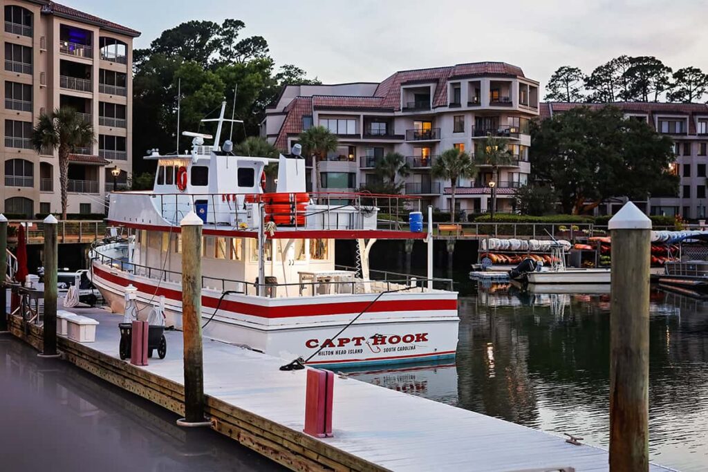 The Capt. Hook vessel is docked at Shelter Cove Marina in Hilton Head with 5-story condos visible in the background