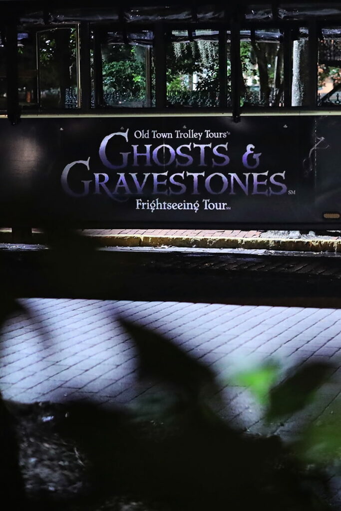 Nighttime shot of the Ghosts and Gravestones logo on the side of a black Savannah ghost tours trolley