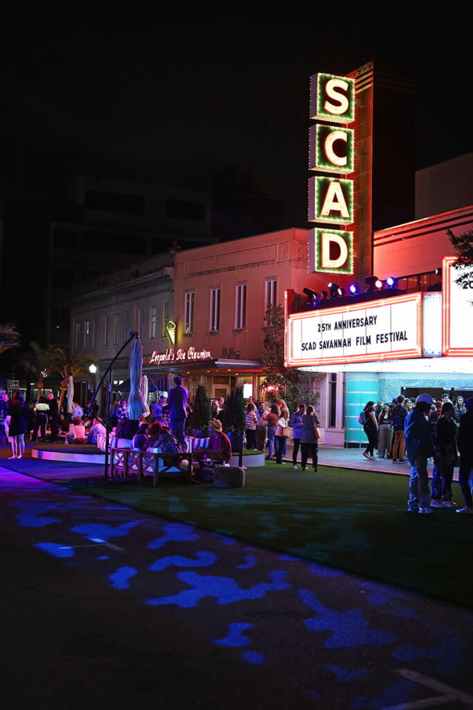 Nighttime scene of the SCAD sign on Broughton Street illuminating a crowd of attendees at the Savannah film festival, one of the largest annual events in Savannah