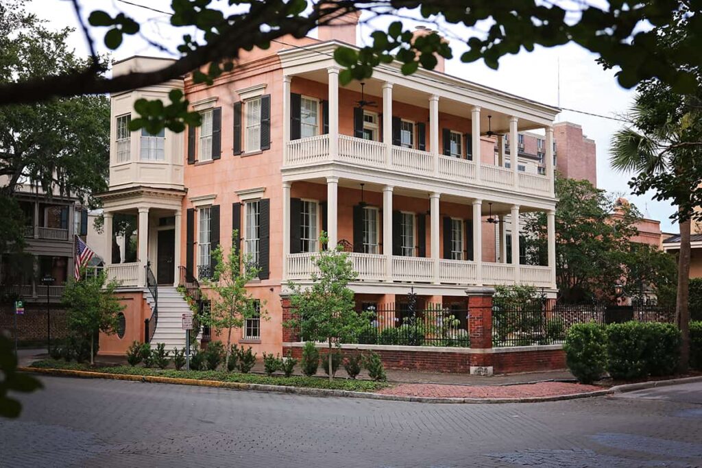 Peach-colored mansion at 432 Abercorn Street with side porches stretching across both the second and third stories and an elegant curved staircase leading to the front door