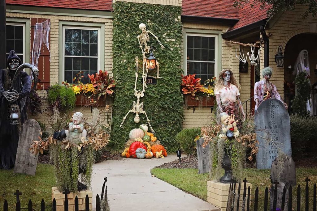 The front yard of a home in Ardsley Park is decorated for Halloween with skeletons scaling a moss-covered wall, Chucky dolls in positioned in planters along the sidewalks, and zombies peeking out from headstones partially buried in the lawn
