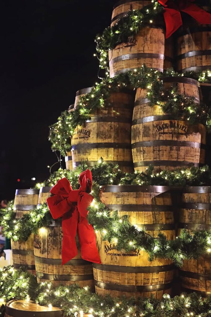 Close-up view of a Christmas tree made of empty barrels of Jack Daniels Whiskey draped in lighted garlands and red ribbons at the Savannah Christmas Market
